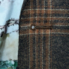 Detailed macro shot of hand-sewn Milanese buttonhole stitching on brown rust block windowpane sport coat lapel