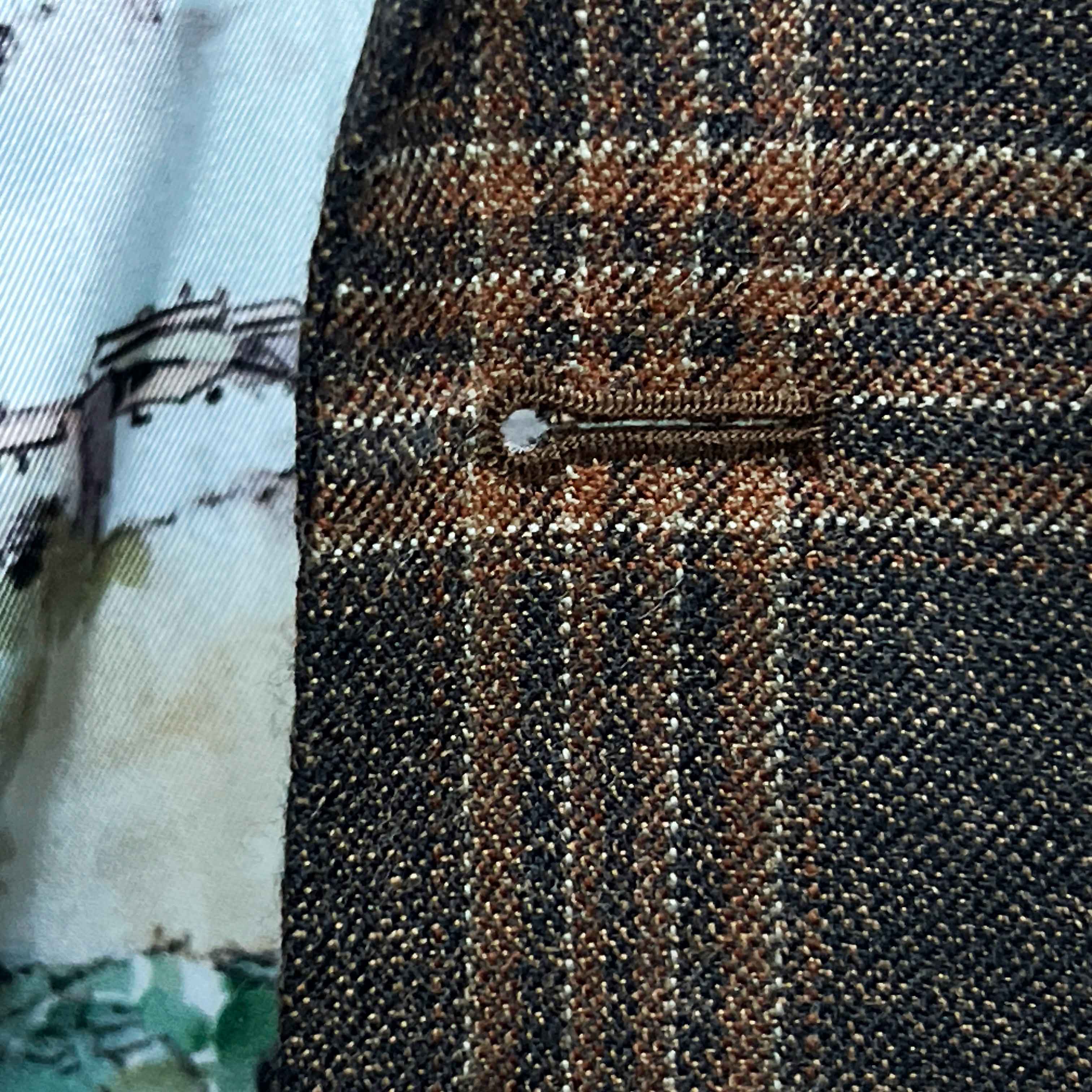 Detailed macro shot of hand-sewn Milanese buttonhole stitching on brown rust block windowpane sport coat lapel
