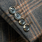 Sport coat sleeve cuff showing functional buttonholes on brown rust block windowpane tweed fabric