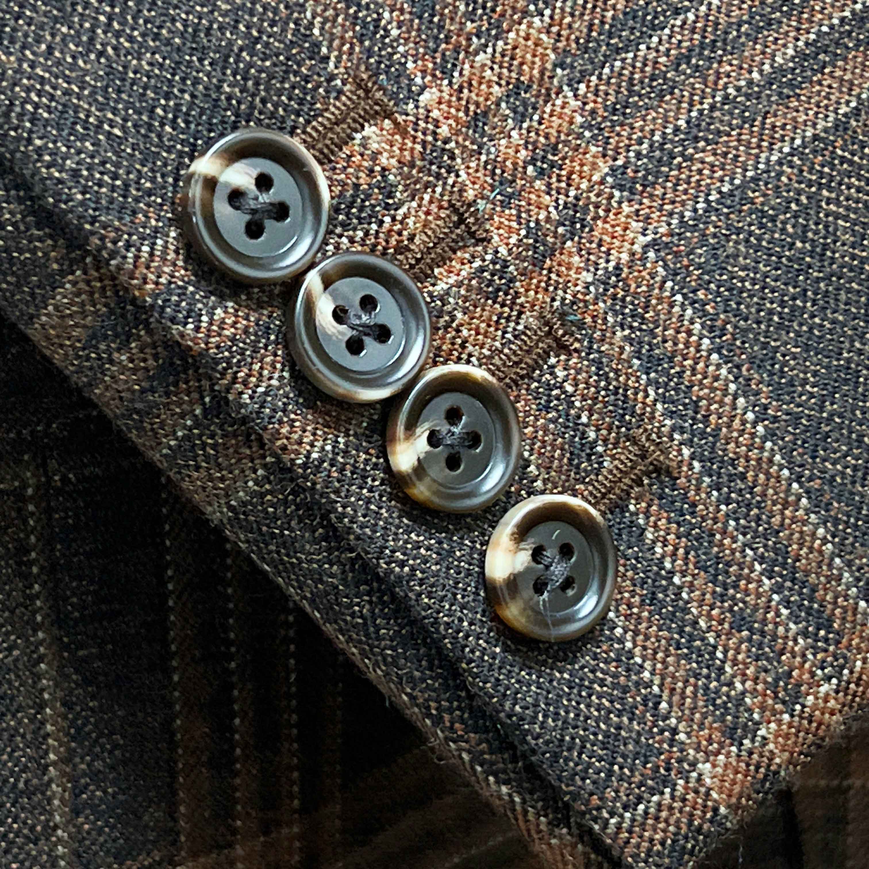 Sport coat sleeve cuff showing functional buttonholes on brown rust block windowpane tweed fabric