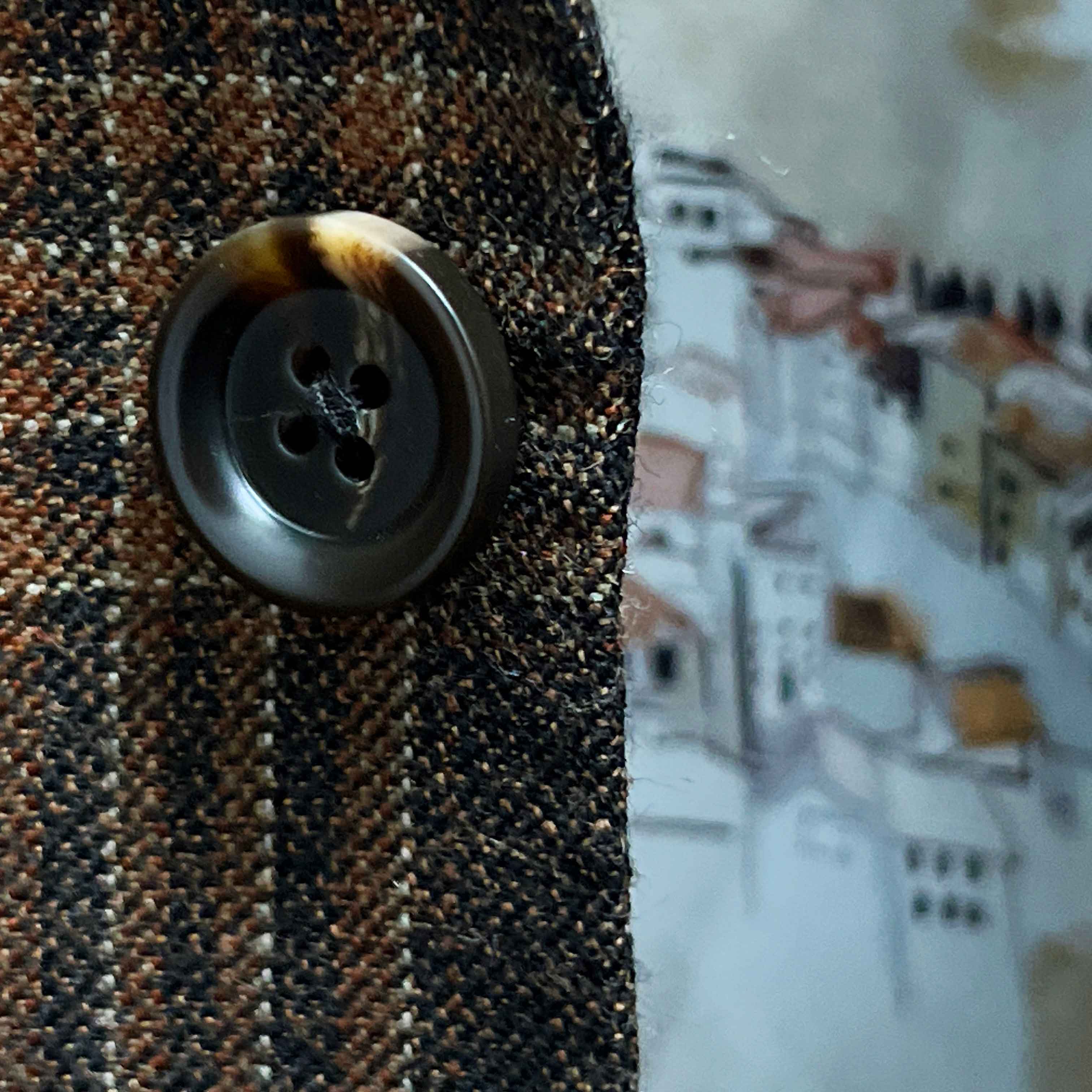 Close-up of walnut dark brown and amber horn buttons on brown rust block windowpane sport coat showing natural patterns