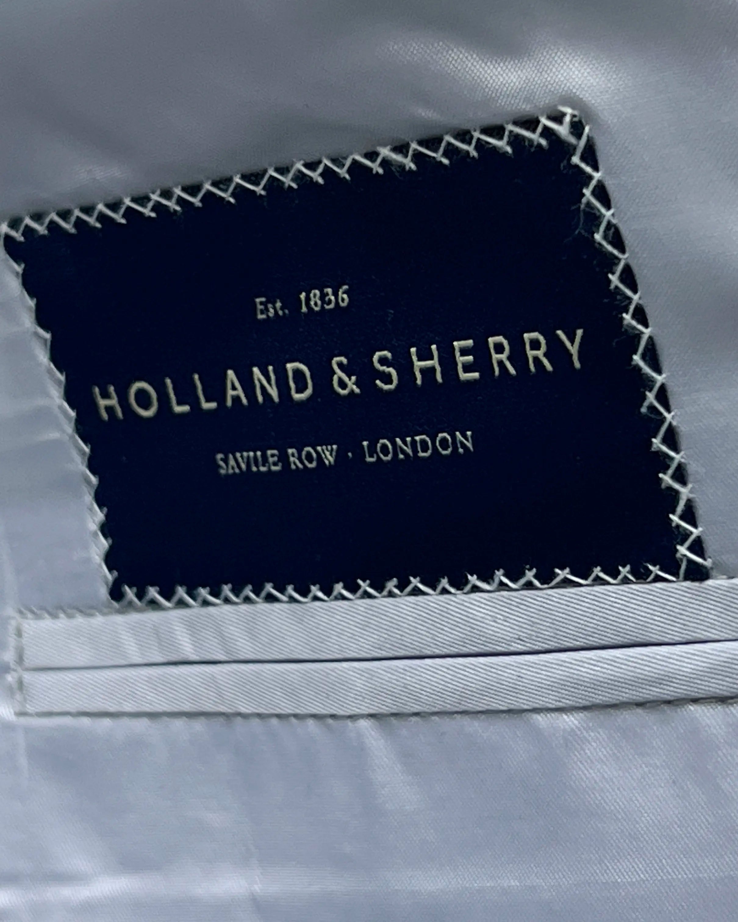 Mill label detail of light tan hopsack men's sport coat showing the Holland and Sherry cloth label