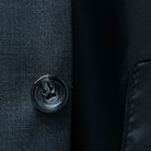 Horn buttons enhancing the traditional elegance of a dark gray sharkskin suit.
