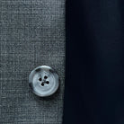 Durable horn buttons adding a classic touch to a dark grey nailhead suit.