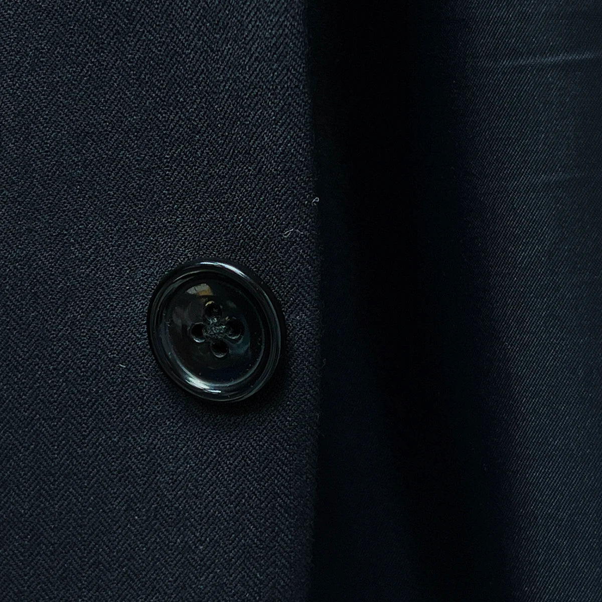 Elegant horn marble buttons enhancing the black herringbone fabric.