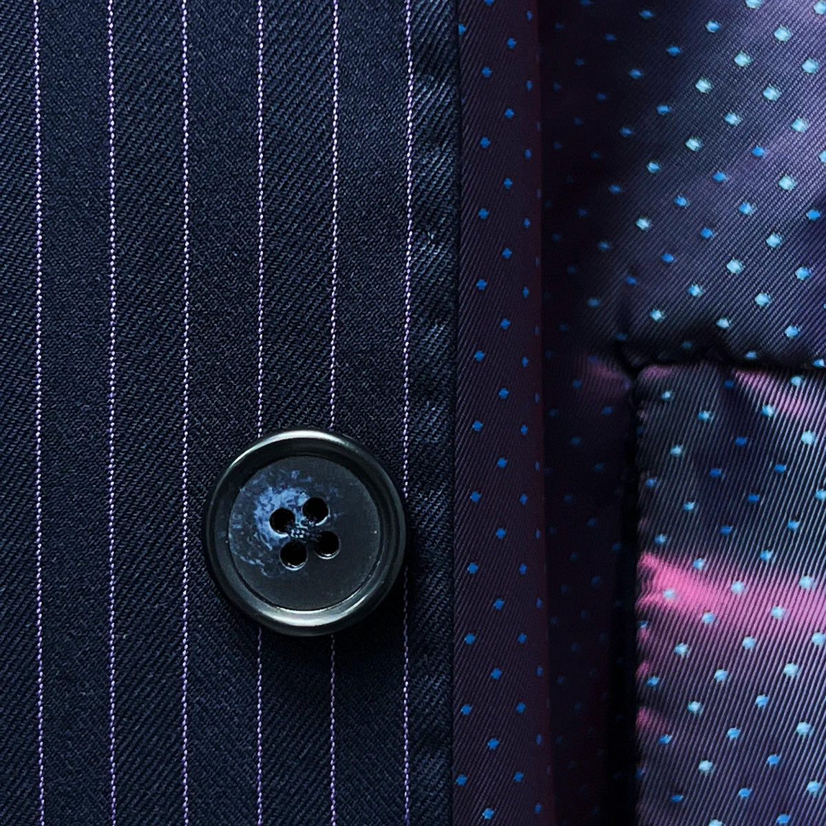 Horn marble buttons enhancing the refined look of a navy suit with purple pinstripes.