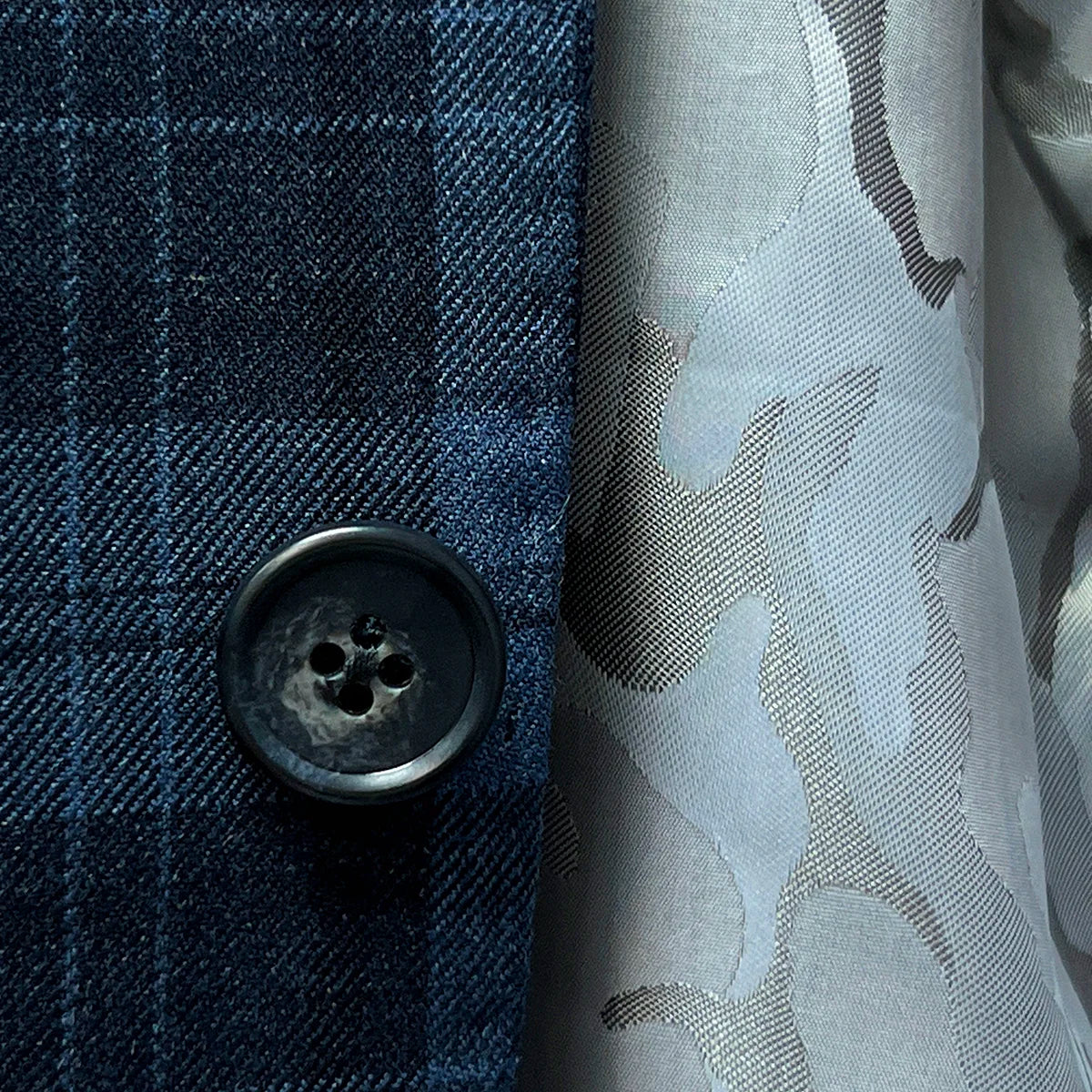 Detailed view of horn marble buttons on a Prussian Blue sportcoat with black grid checks.