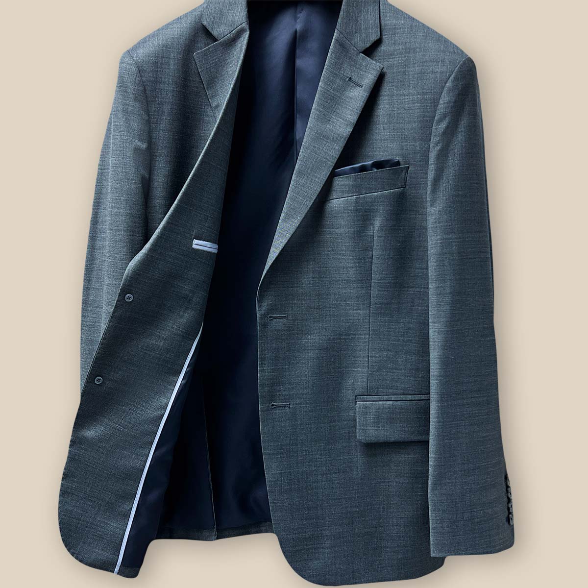 Inside view of the jacket showcasing the lining and construction of a dark grey nailhead suit.