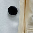View of the black satin covered buttons on the ivory tuxedo jacket, showcasing their smooth finish and luxurious look.