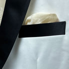 Close-up of the built-in pocket square in the ivory tuxedo jacket, with black silk satin detailing on the upper breast pocket.
