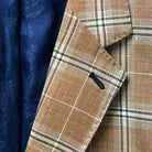 Lapel buttonhole detailing on a brown beige men's sport coat with blanched almond and midnight blue windowpane pattern.