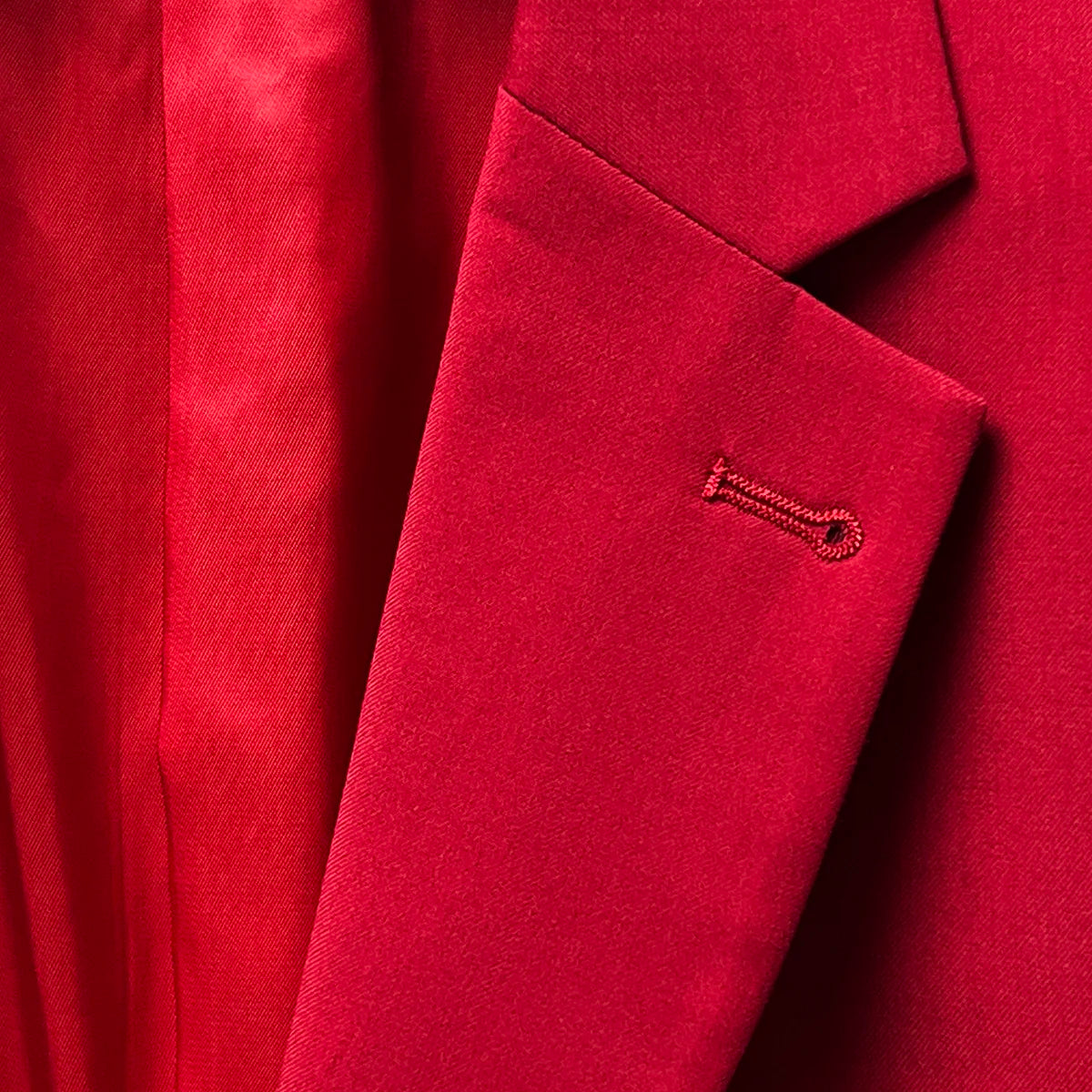 Lapel buttonhole showcasing a classic tailoring detail on a scarlet red, solid plain color suit.