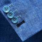 Detail of light blue solid Irish linen men's suit jacket sleeve showing functional buttonholes, including royal blue accent buttonhole
