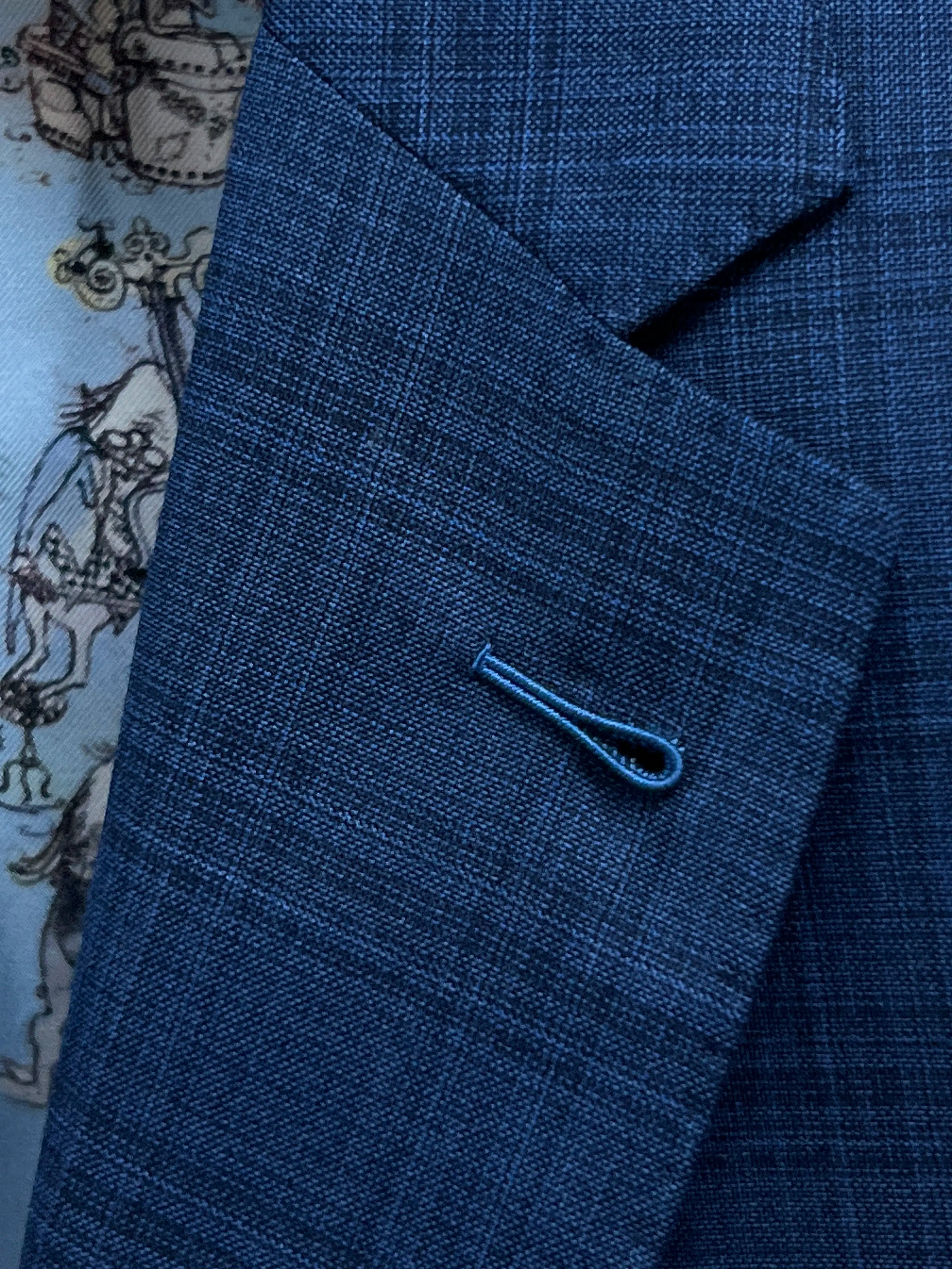 Lapel buttonhole detail of blue windowpane check men's suit showing Milanese lapel buttonhole