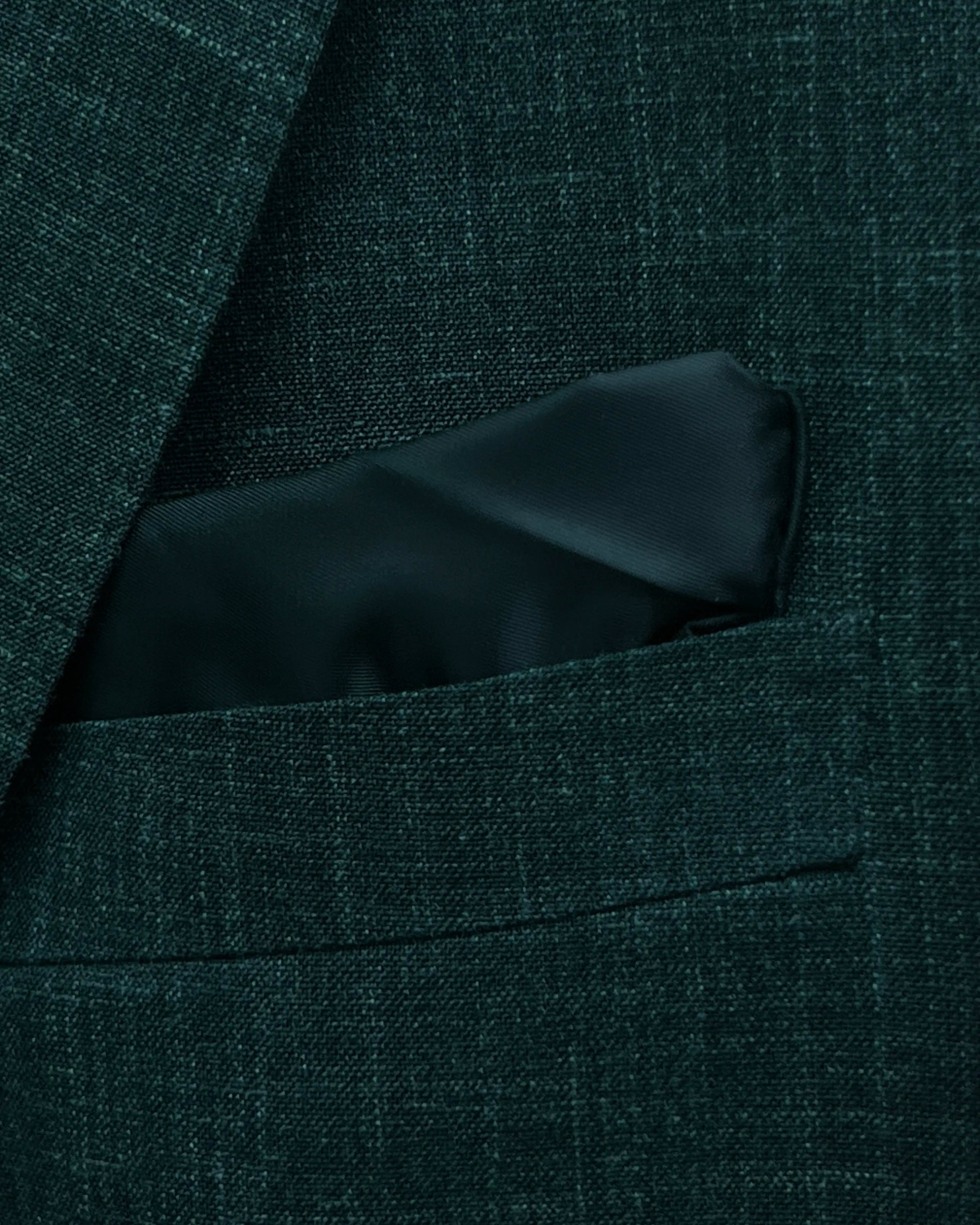 Pocket square detail image of deep green solid men's suit showing built in pocket square matching the lining