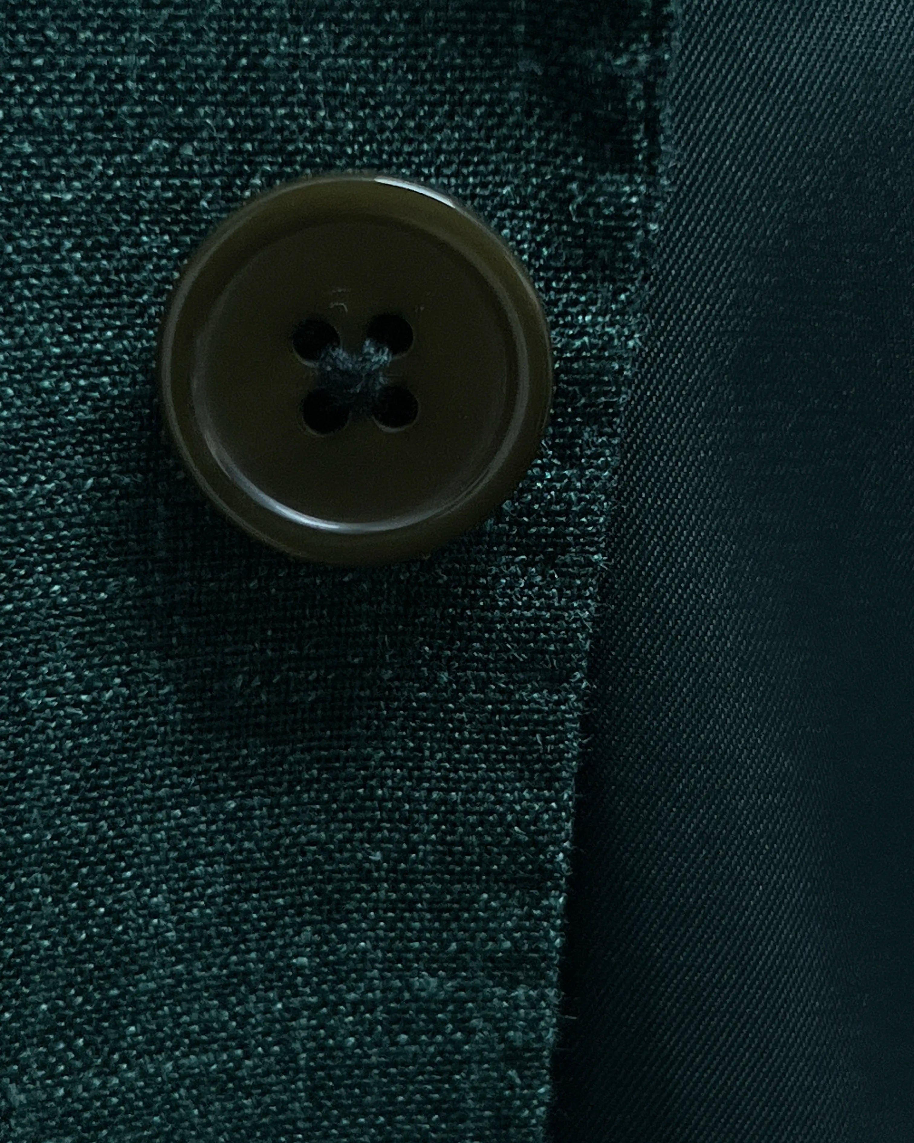 Button detail image of deep green solid men's suit showing dark olive horn buttons