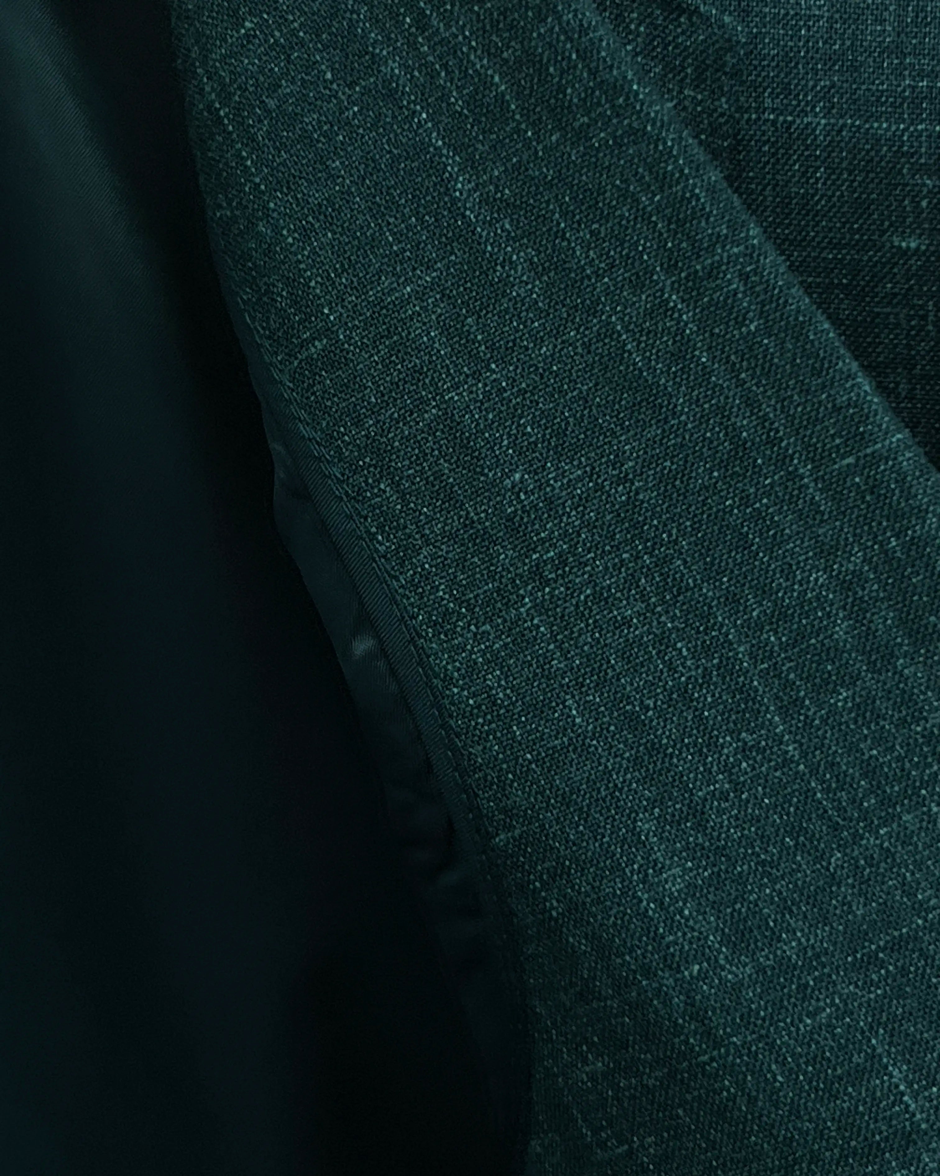 Fabric texture close up of deep green solid men's suit showing textured slub weave with visible crosshatch yarn definition