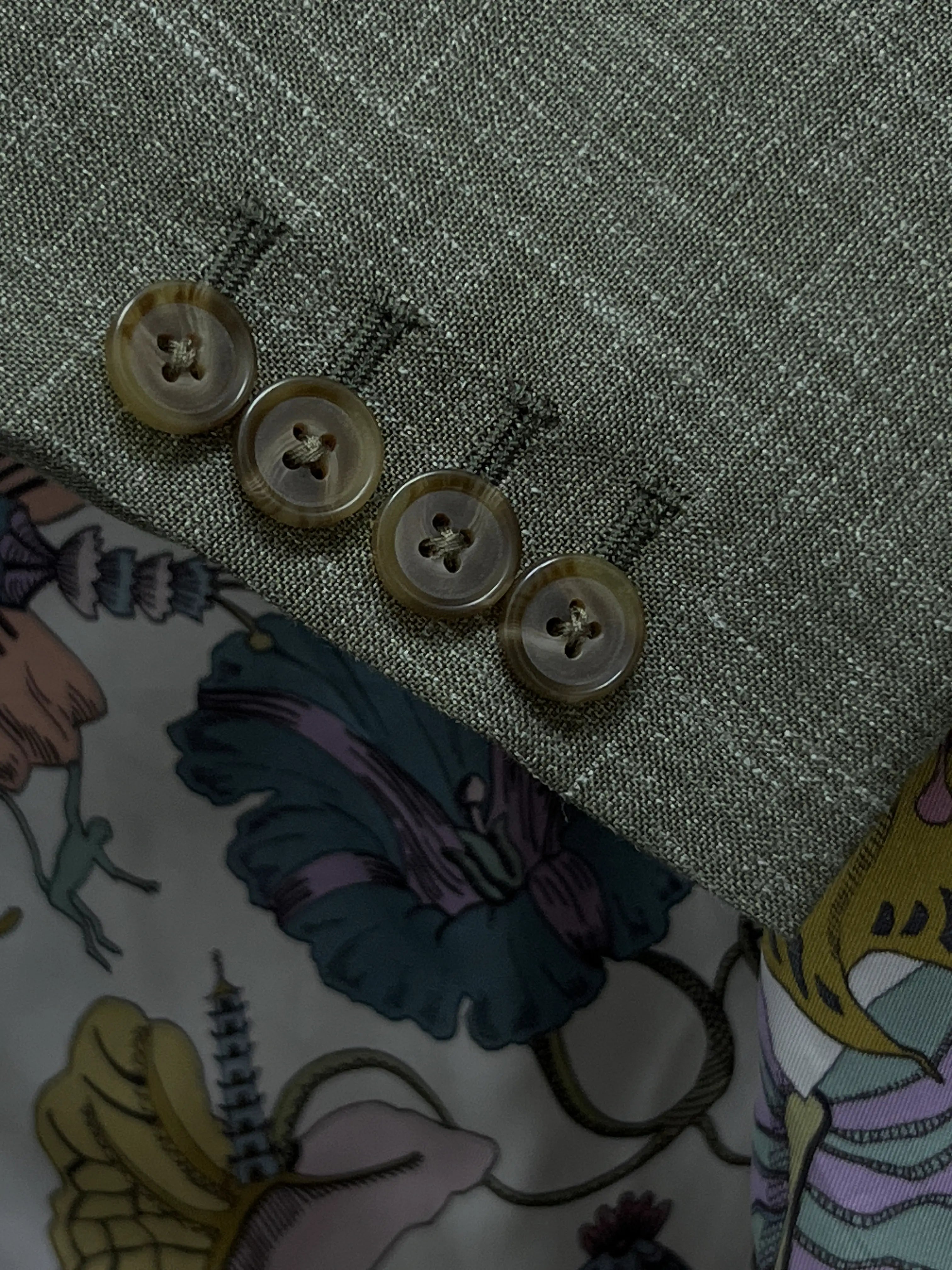 Sleeve cuff of sage green plain men's suit showing four functional surgeon's buttonholes