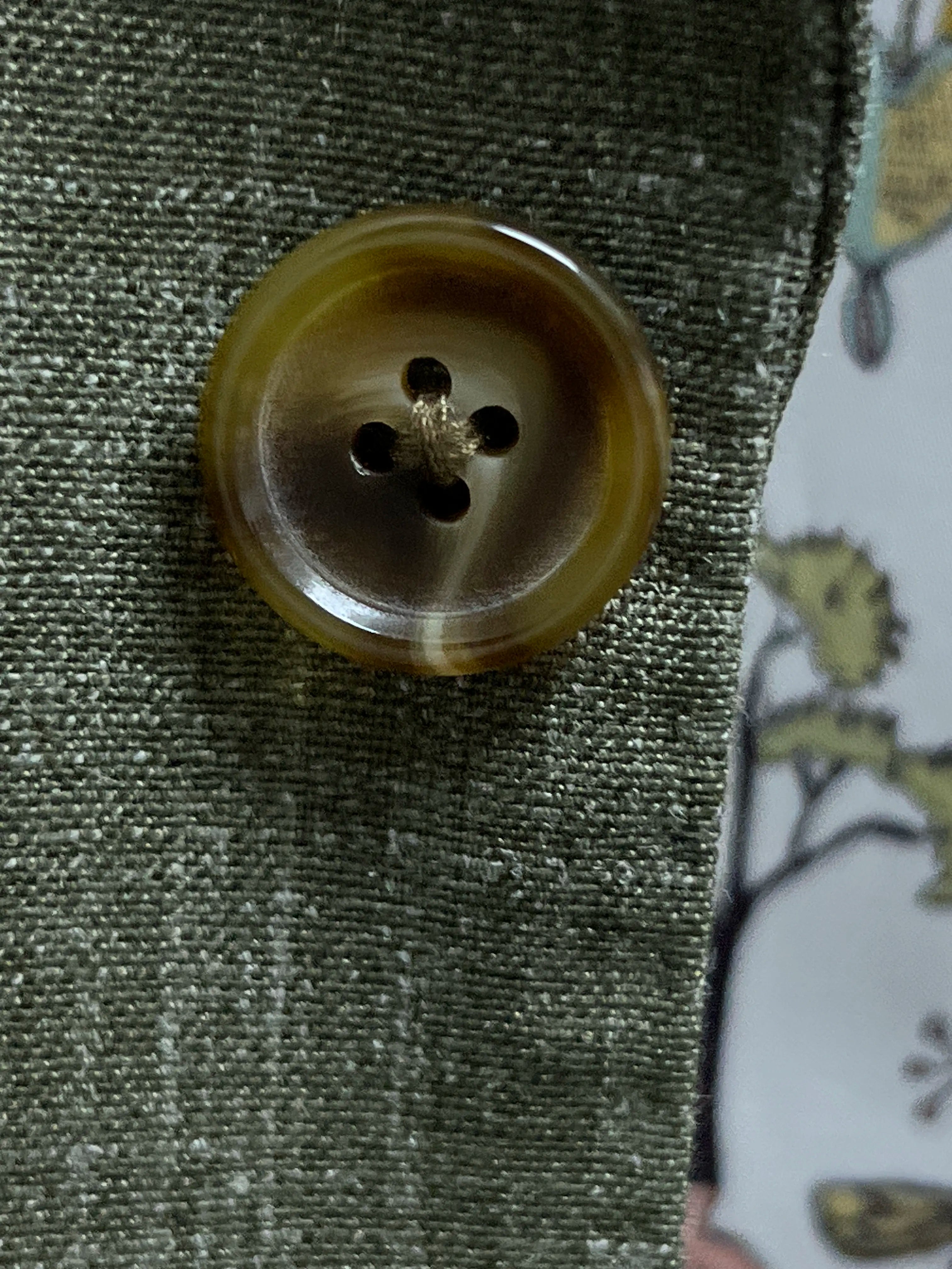 Close-up of olive khaki horn buttons on sage green plain men's suit