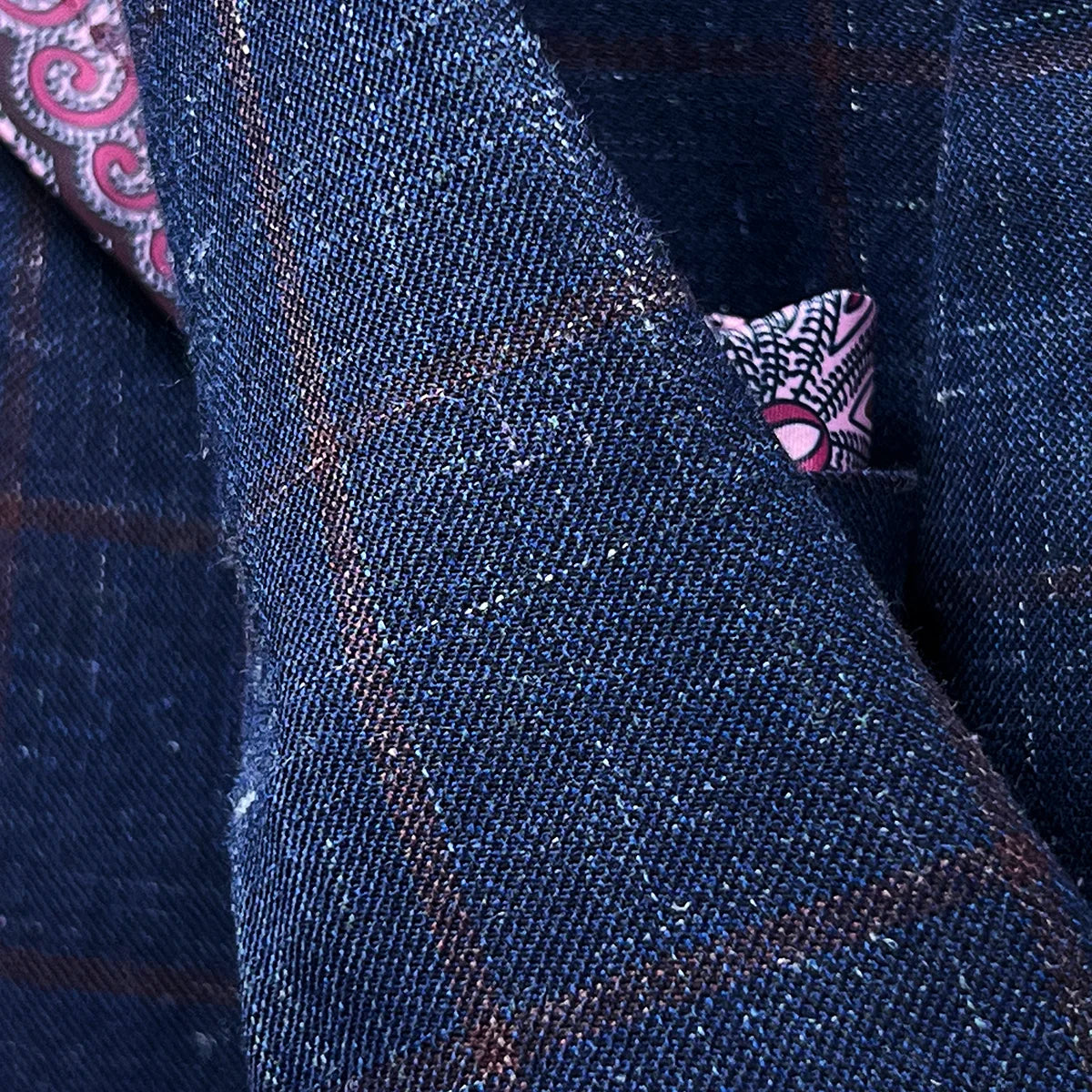Detailed view of hand-picked stitching along lapel edges and seams of navy windowpane sport coat showing artisan craftsmanship