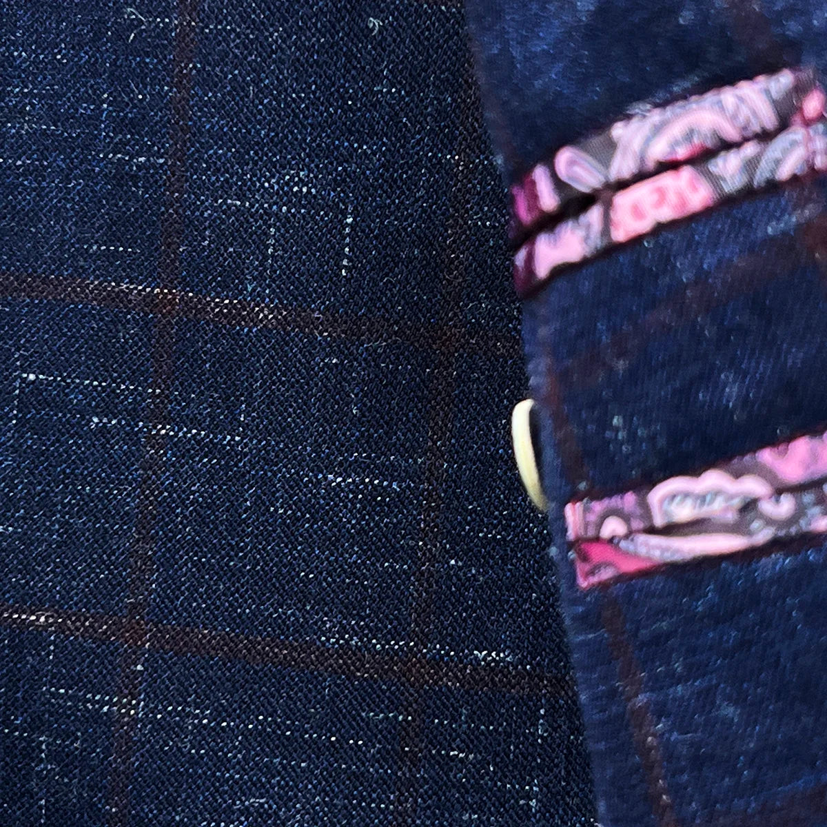 Close-up of lapel buttonhole with ruby red contrast stitching on navy windowpane sport coat peak lapel showing precision tailoring work