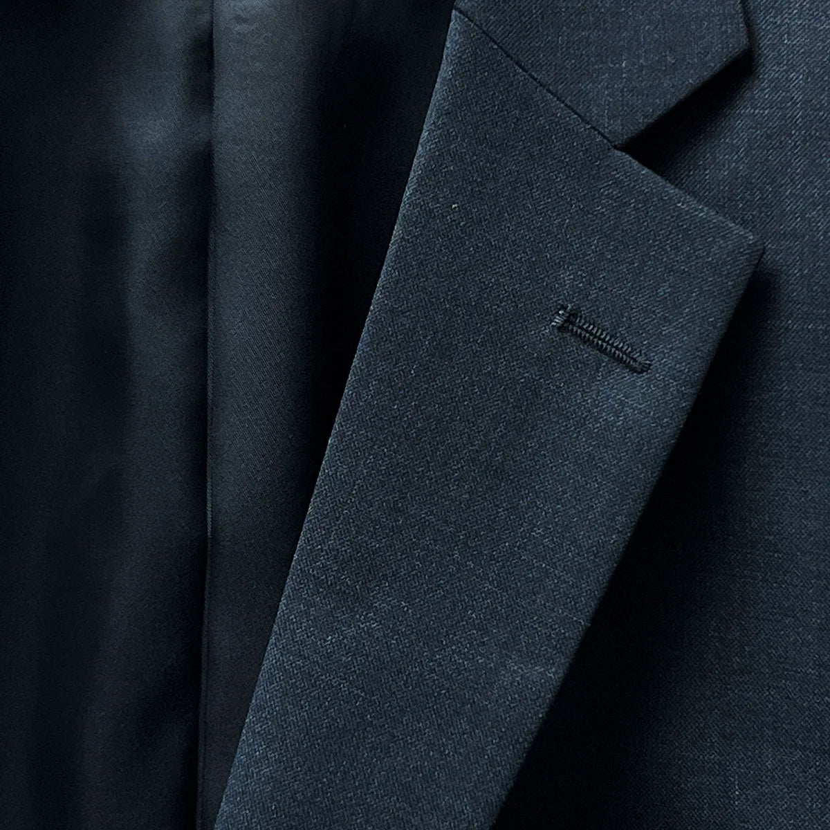 Notch lapel presenting a classic silhouette on a dark gray sharkskin suit.