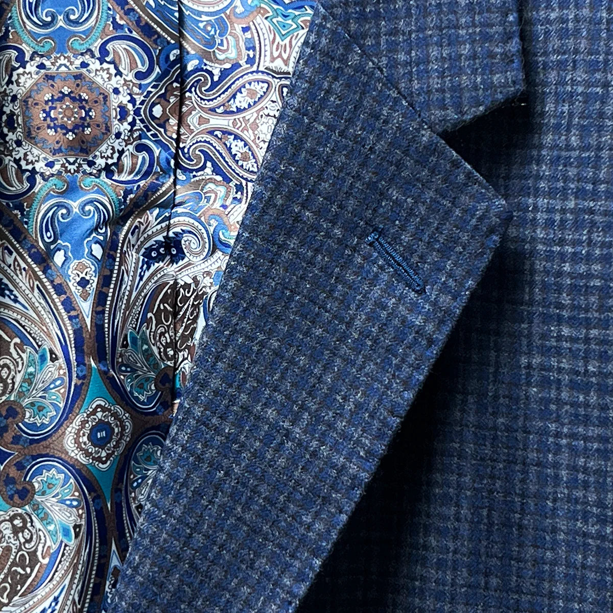 Notch lapel providing a formal look to a gray blue mini grid checks sport coat made of flannel wool.