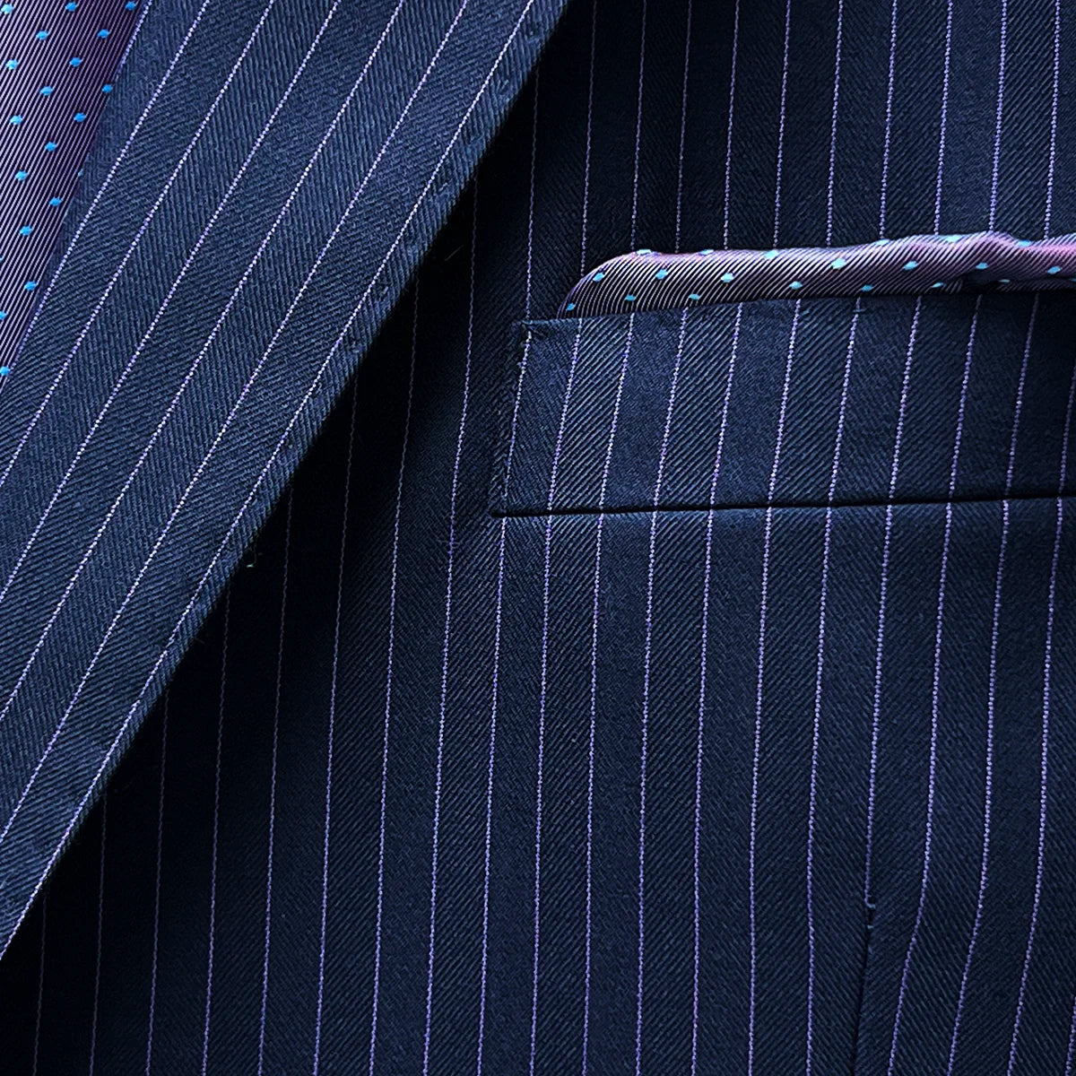 Pocket square adding a dash of elegance to a navy suit with purple pinstripes.