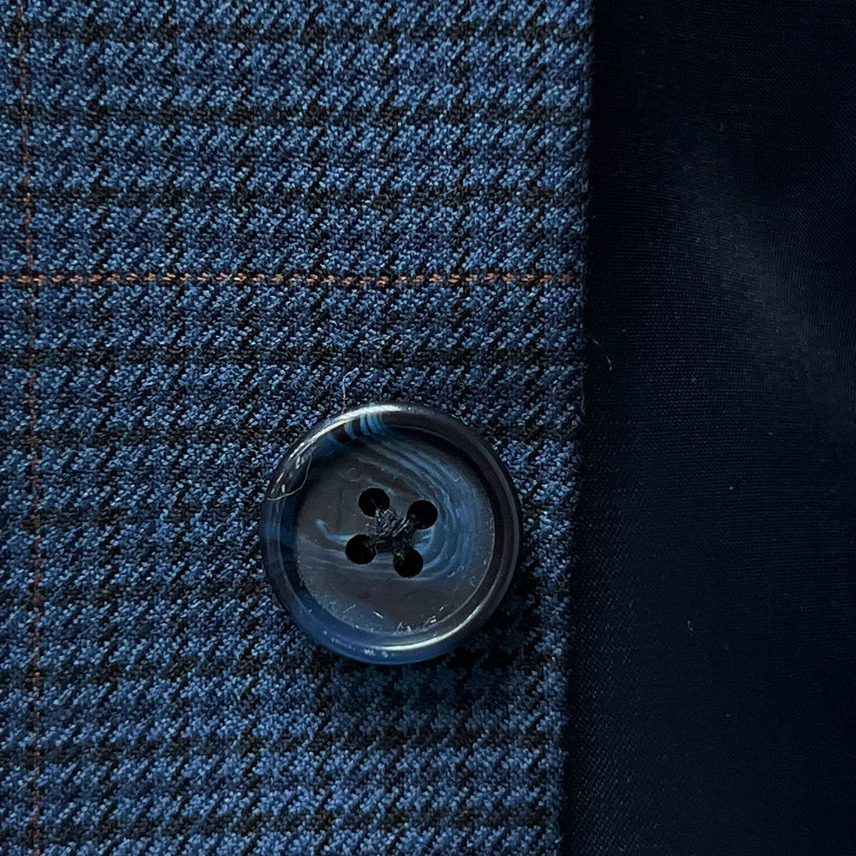 Close-up of the navy marble horn buttons on the prussian blue suit jacket, highlighting their unique texture and color.