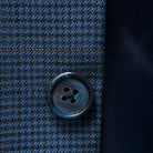Close-up of the navy marble horn buttons on the prussian blue suit jacket, highlighting their unique texture and color.