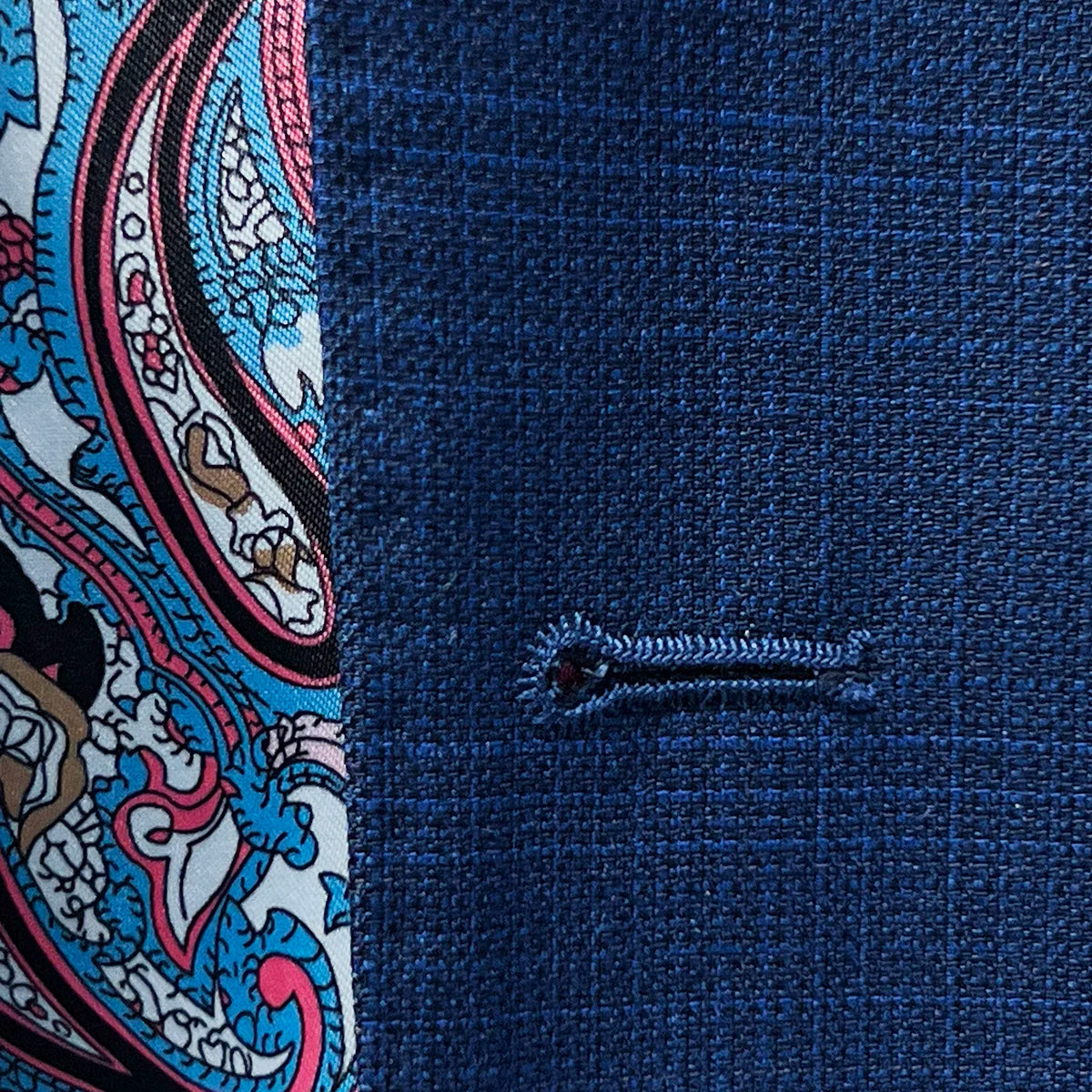 Detailed view of the buttonhole stitching on the royal blue suit.