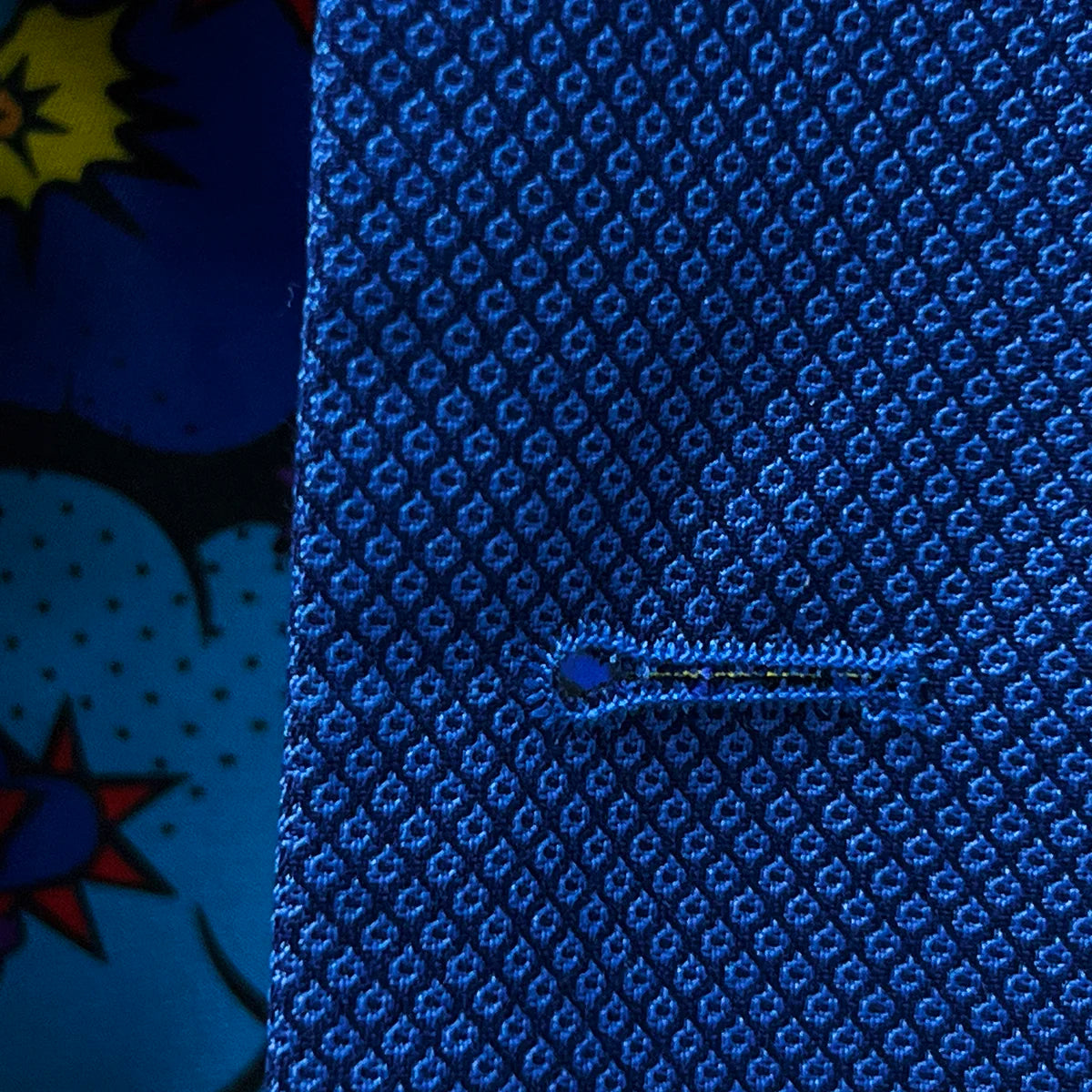 Detailed view of the buttonholes of the sapphire blue men's suit.