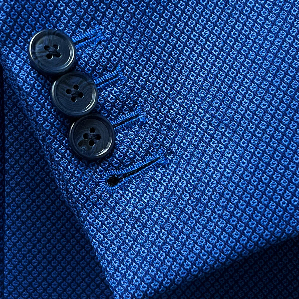 Close-up view showing the functional sleeve buttonholes with contrast stitching on the sapphire blue men's suit, enhancing its functionality and style.