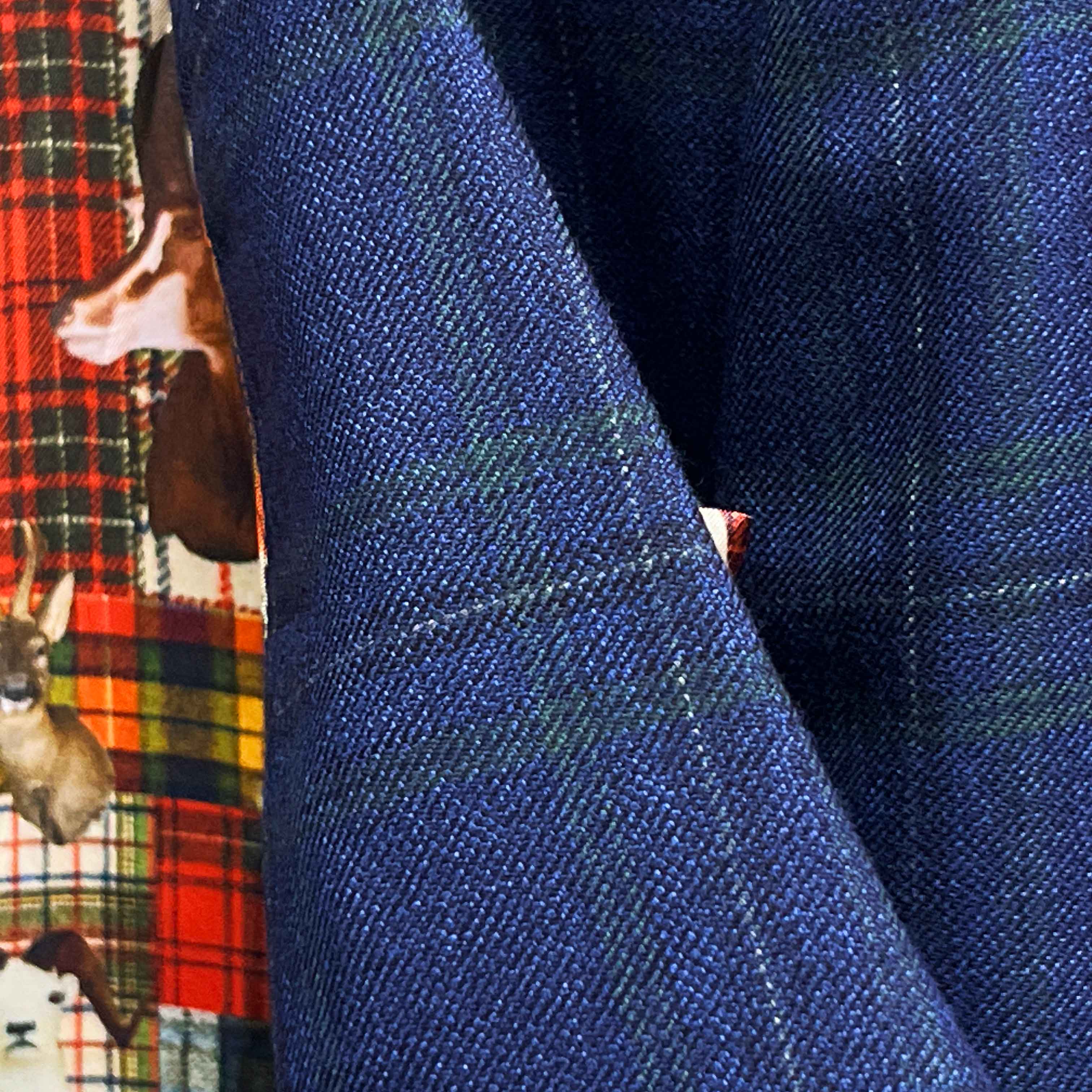 Macro detail of Scabal deep blue navy emerald green overcheck fabric showing twill weave texture and plaid pattern