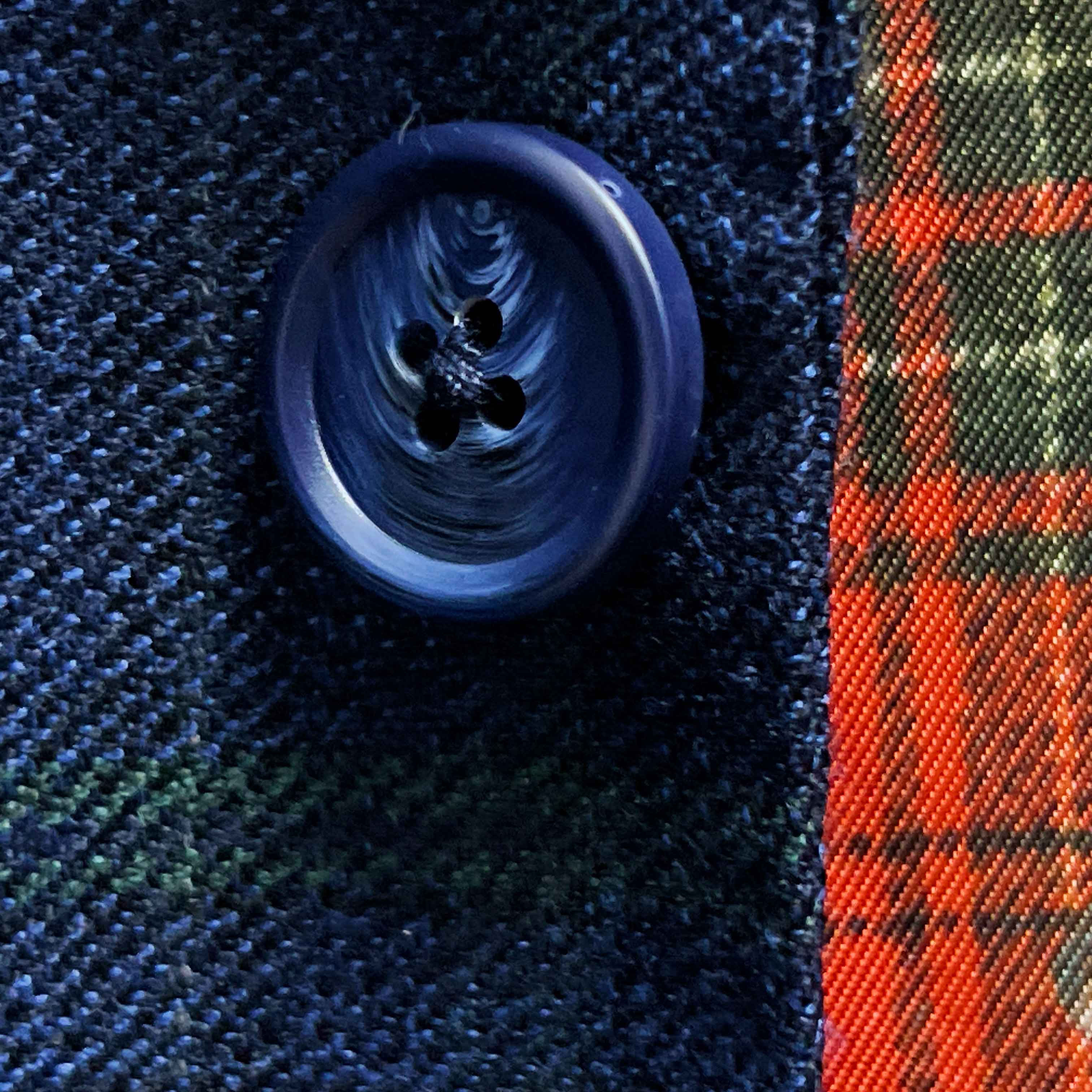 Close-up of navy marble horn buttons on deep blue navy emerald green overcheck suit jacket showing natural marble-like patterns