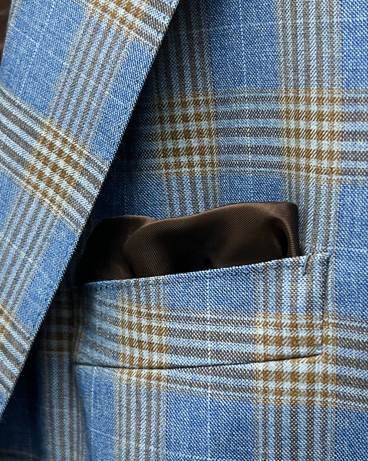 Pocket square detail of light blue with tobacco brown glen check men's sport coat showing the matching lining pocket square