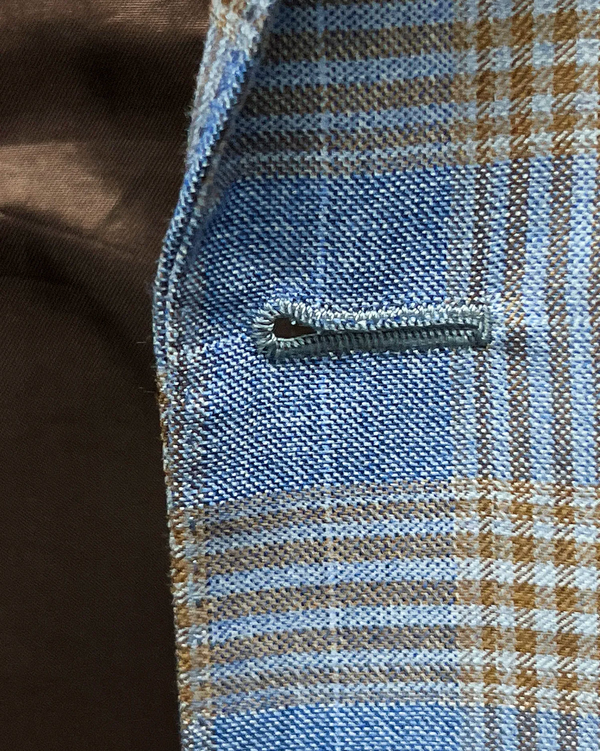 Buttonhole detail of light blue with tobacco brown glen check men's sport coat showing front buttonhole stitching