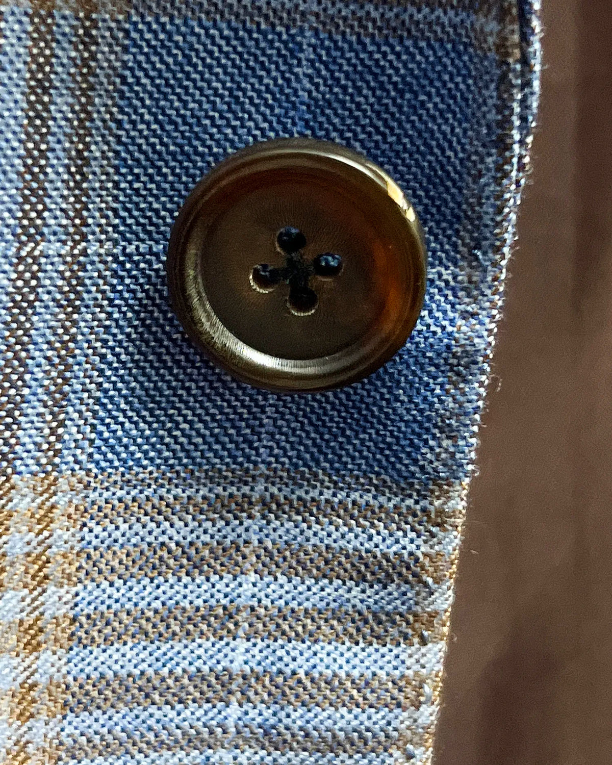 Button detail of light blue with tobacco brown glen check men's sport coat showing dark brown horn buttons