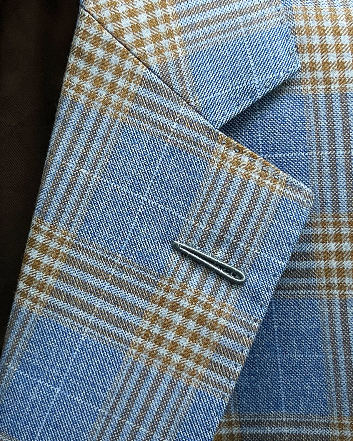 Lapel detail of light blue with tobacco brown glen check men's sport coat showing the Milanese lapel buttonhole