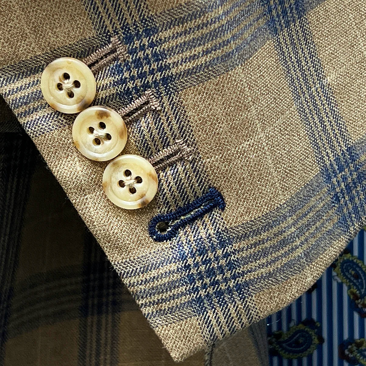 Close-up of working sleeve buttonholes with navy blue accent stitching