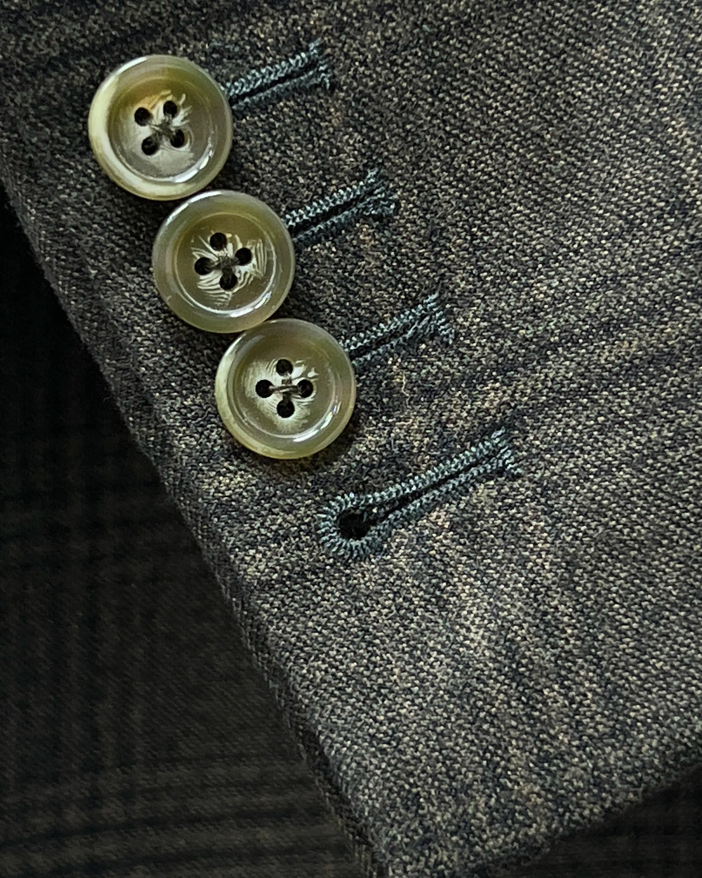 Sleeve cuff close up of charcoal brown melange tonal Glen Plaid men's sport coat showing functional sleeve buttons with matching thread.