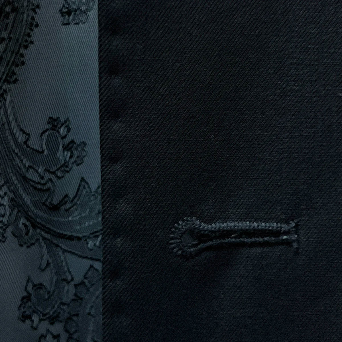 Macro shot of precise buttonhole stitching on a black Vitale Barberis Canonico suit, showcasing the craftsmanship.