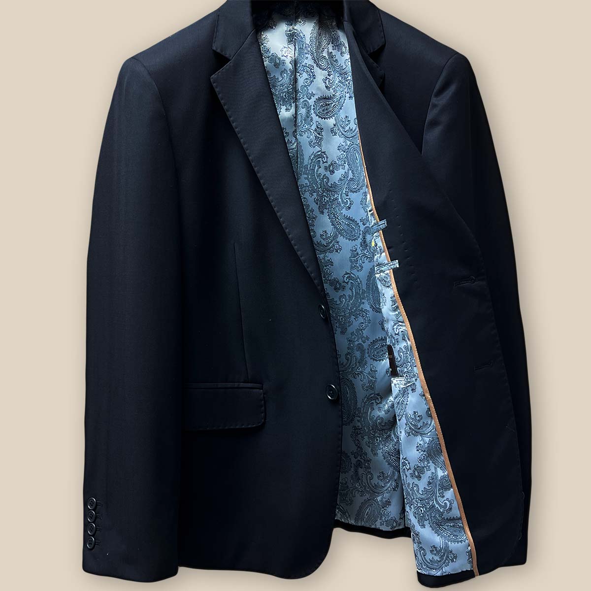 Interior view of the left side of a black Vitale Barberis Canonico suit jacket, revealing silver paisley lining and inner pockets.