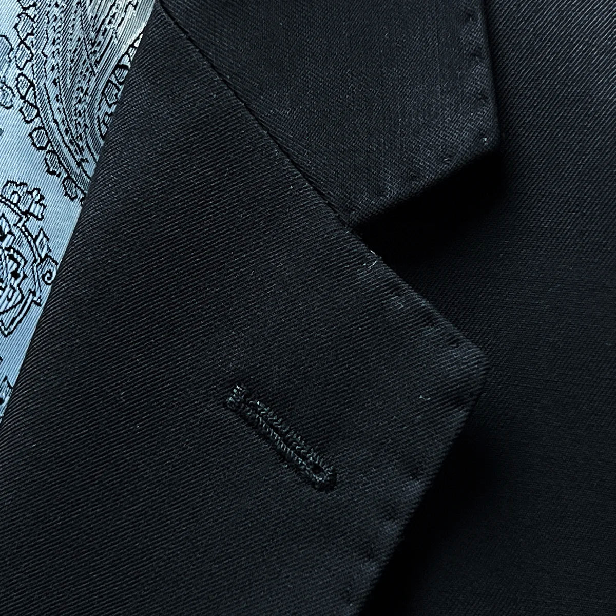 Detailed view of the notch lapel on a black Vitale Barberis Canonico suit jacket, showing its clean lines and pick stitching.