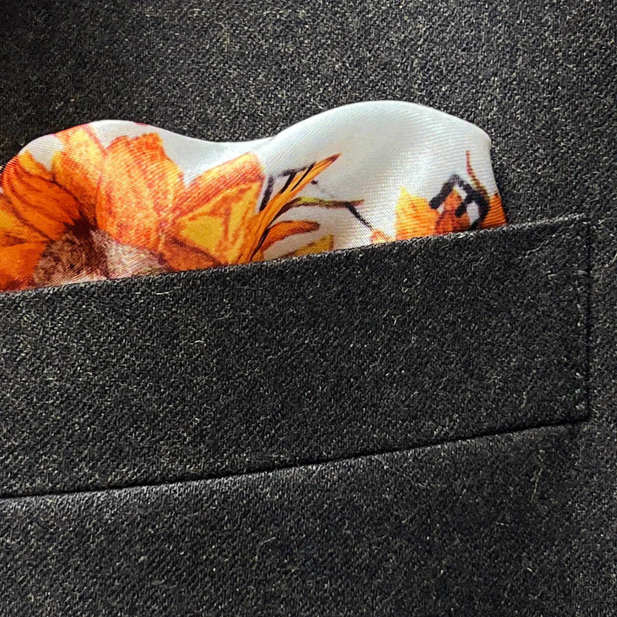 Breast pocket of dark brown plain weave suit jacket with built-in pocket square holder and hand-finished edges