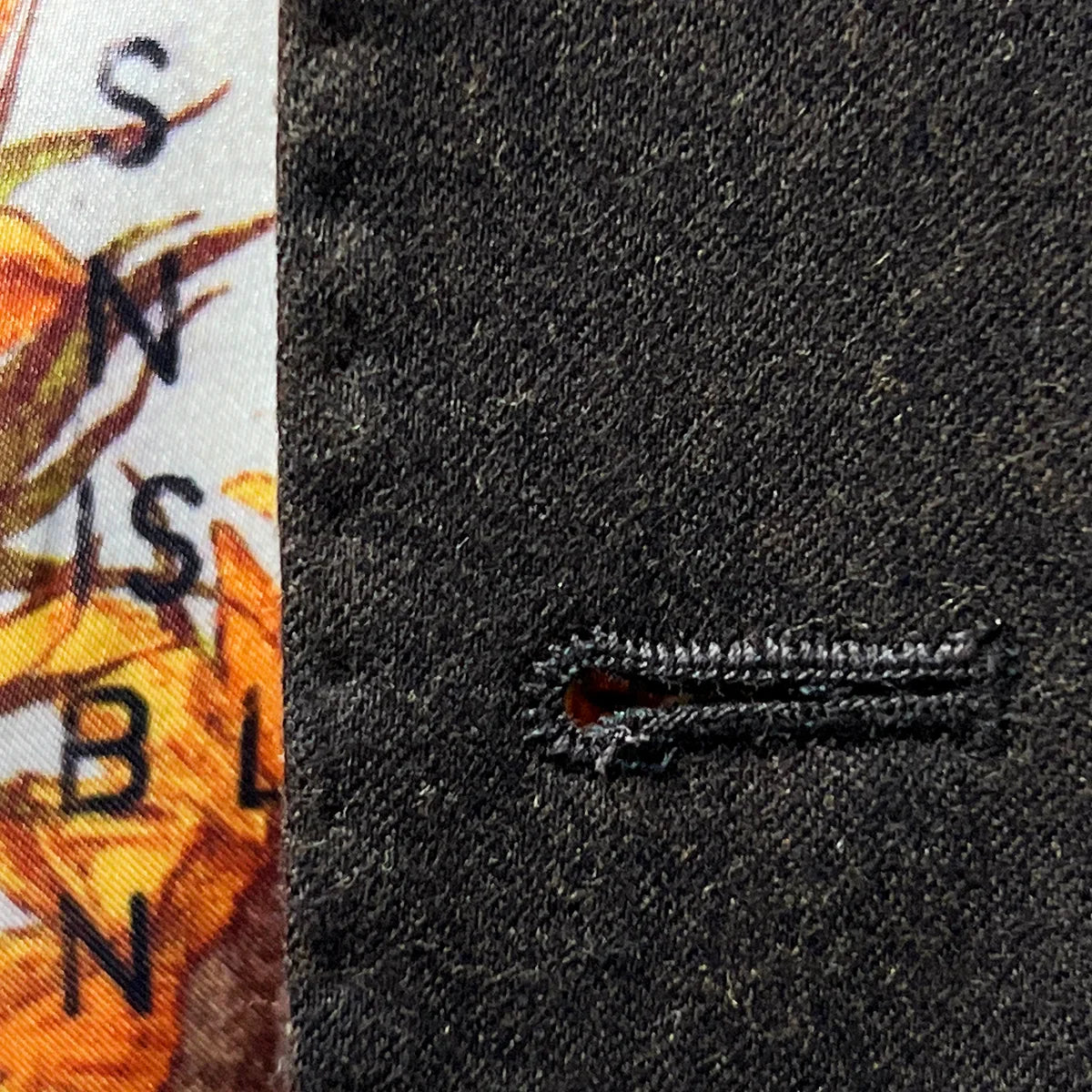Detailed macro shot of hand-finished buttonhole stitching on dark brown plain weave suit with medium brown contrast thread