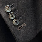 Suit jacket sleevecuff showing functional buttonholes with contrast medium brown accent stitching on dark brown plain weave fabric