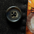Close-up of walnut brown horn buttons on dark brown plain weave suit jacket showing natural marble-like patterns