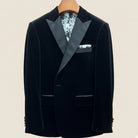 Close-up view of black silk velvet formalwear tuxedo jacket showing satin peak lapel with hand-finished stitching detail