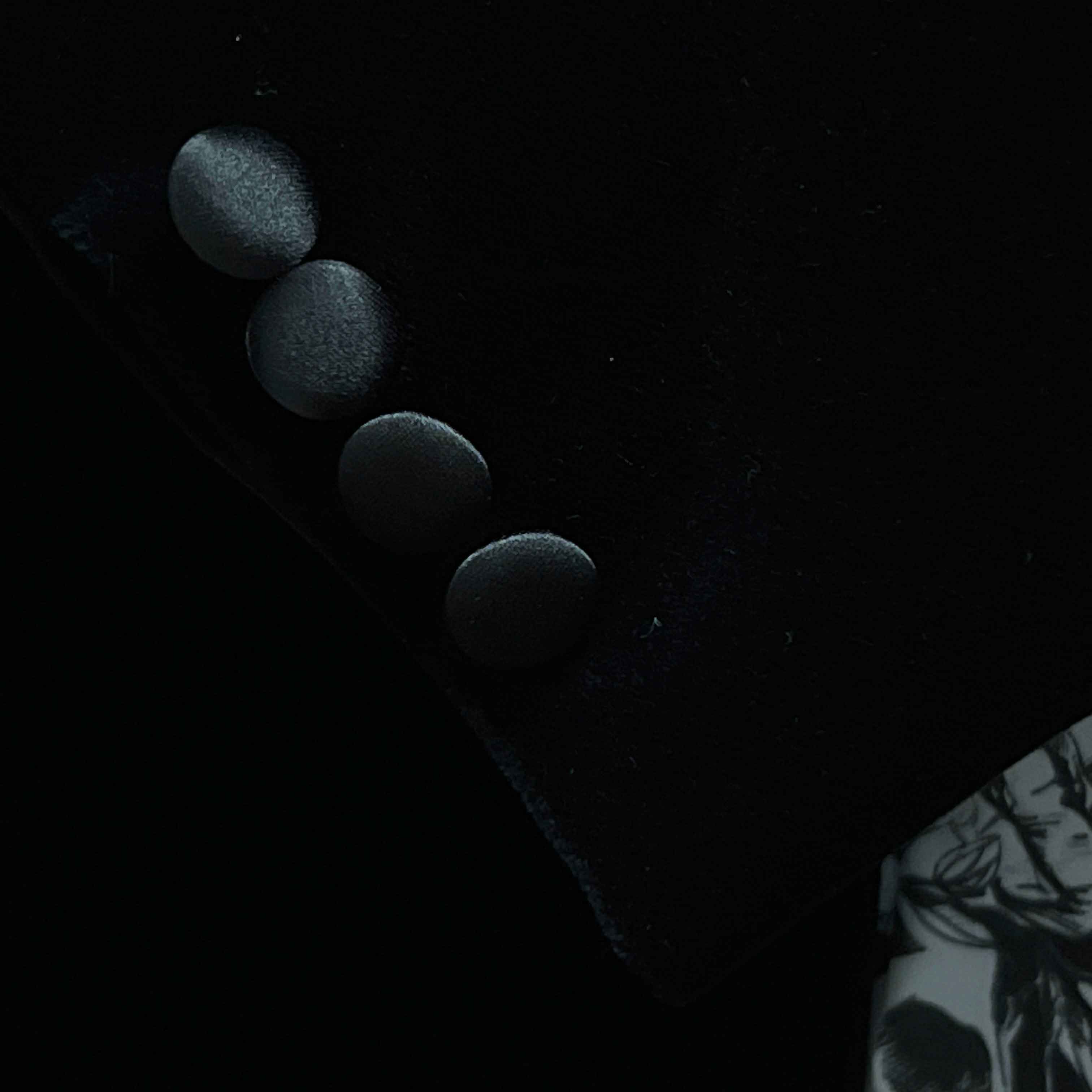 Formalwear tuxedo jacket sleeve cuff showing functional buttonholes with satin trimming on black silk velvet fabric